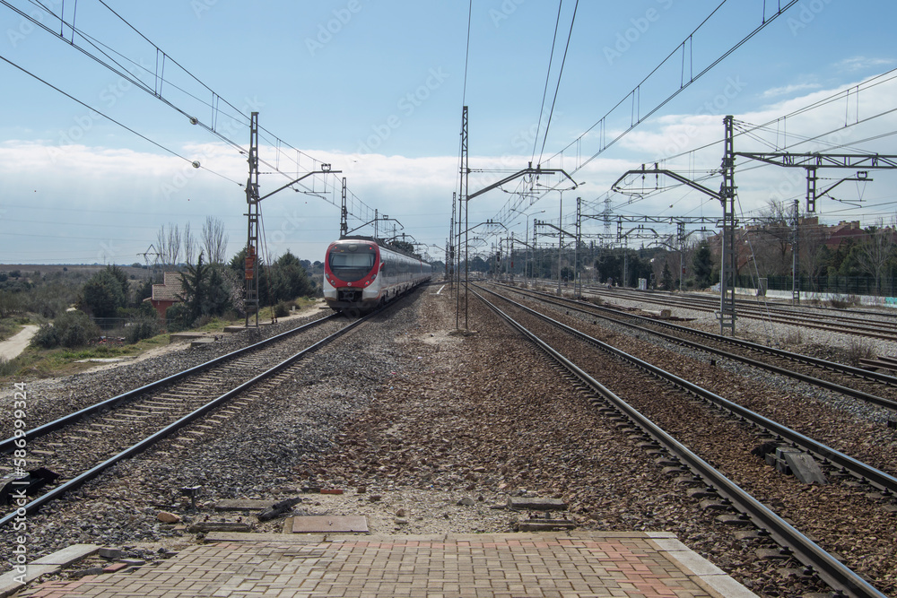 train tracks and power lines with a train in the background of a railway line in Spain