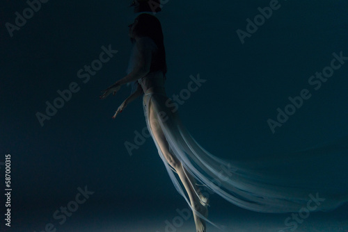 Fototapeta Naklejka Na Ścianę i Meble -  Underwater shoot of beautiful woman in white flying transparent dress swimming in water through sunbeams.