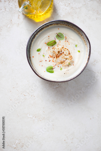 Cream-soup made of cauliflower cabbage on a light-beige stone background, above view, vertical shot, copy space