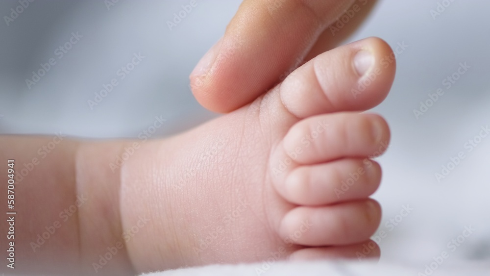 Macro shot of infants toe. Mother touching her small child's toes while he is asleep. Mother touching her sons feet. Mum cares of her infant baby. Close up shot of loving mothers care. Macro shot of infants toe. Mother touching her small child's toes while he is asleep. Mother touching her sons feet. Mum cares of her infant baby. Close up shot of loving mothers care.