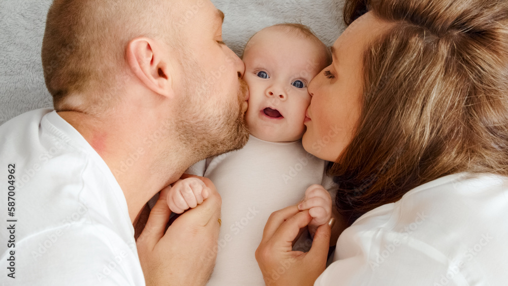 Happy family. Newborn baby with happy parents, top view. Healthy newborn baby in a white t-shirt with mom and dad. Close up Faces of the mother, father and infant baby. Cute Infant boy and parents
