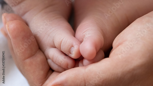 Tiny feet the of a newborn baby in the mother's palms. Mom holds a newborn baby's feet in her hands. Close-up of a newborn baby's feet. Mother loves her baby. The concept of motherhood and parenthood