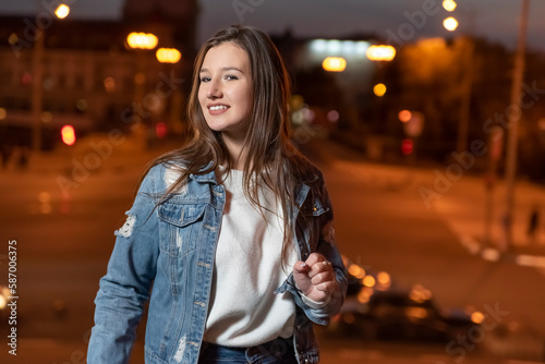 Portrait of smiling stylish brunette girl on evening city background. Young woman in glasses on city street