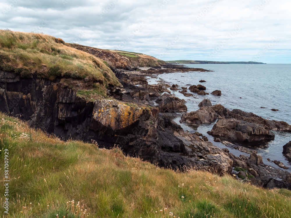Picturesque landscape. Wild vegetation on stony soil. Cloudy sky over the ocean coast. Views on the wild Atlantic way, hills under clouds.