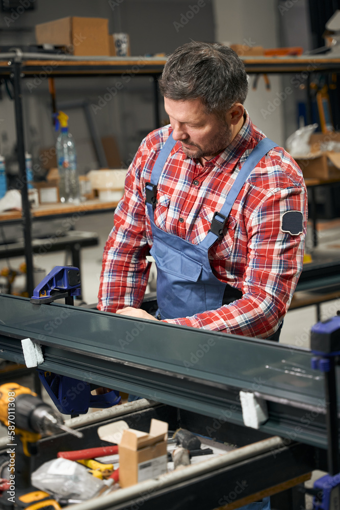 Adult worker connecting metal parts in factory Adult worker connecting metal parts in factory