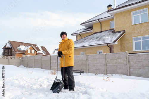 Man removing snow from sidewalk after snowfall. Portrait of man with dog during winter time © lelechka