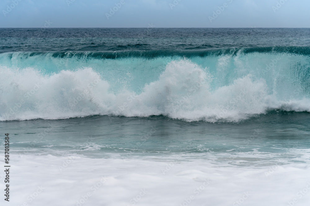 Clear blue sea wave crashing on a cloudy day. Climate nature concept. Front view of a stormy sea.