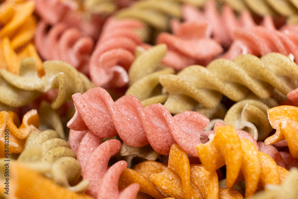 Rice vegetable pasta in the form of spirals, top view. Healthy rice pasta with tomatoes, selenera, carrots and beets Rice vegetable pasta in the form of spirals, top view. Healthy rice pasta with tomatoes, selenera, carrots and beets