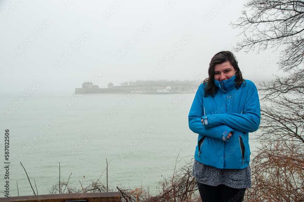 A woman stands at the mouth of the Niagara River on Lake Ontario during a foggy and rainy day