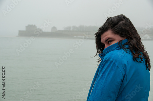 A woman stands at the mouth of the Niagara River on Lake Ontario during a foggy and rainy day