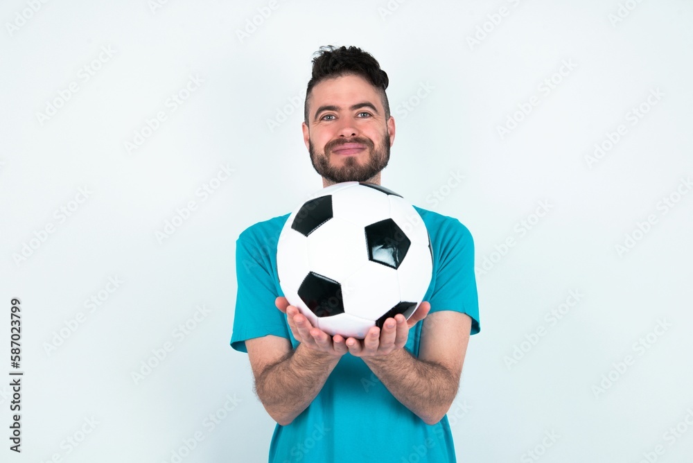 Young man holding a ball over white background holding something with open palms, offering to the camera. Young man holding a ball over white background holding something with open palms, offering to the camera.