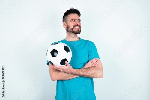 Dreamy rest relaxed Young man holding a ball over white background crossing arms, looks good copyspace © Jihan