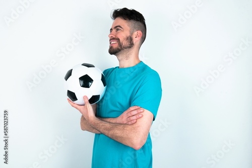 Young man holding a ball over white background cross hands look copy space