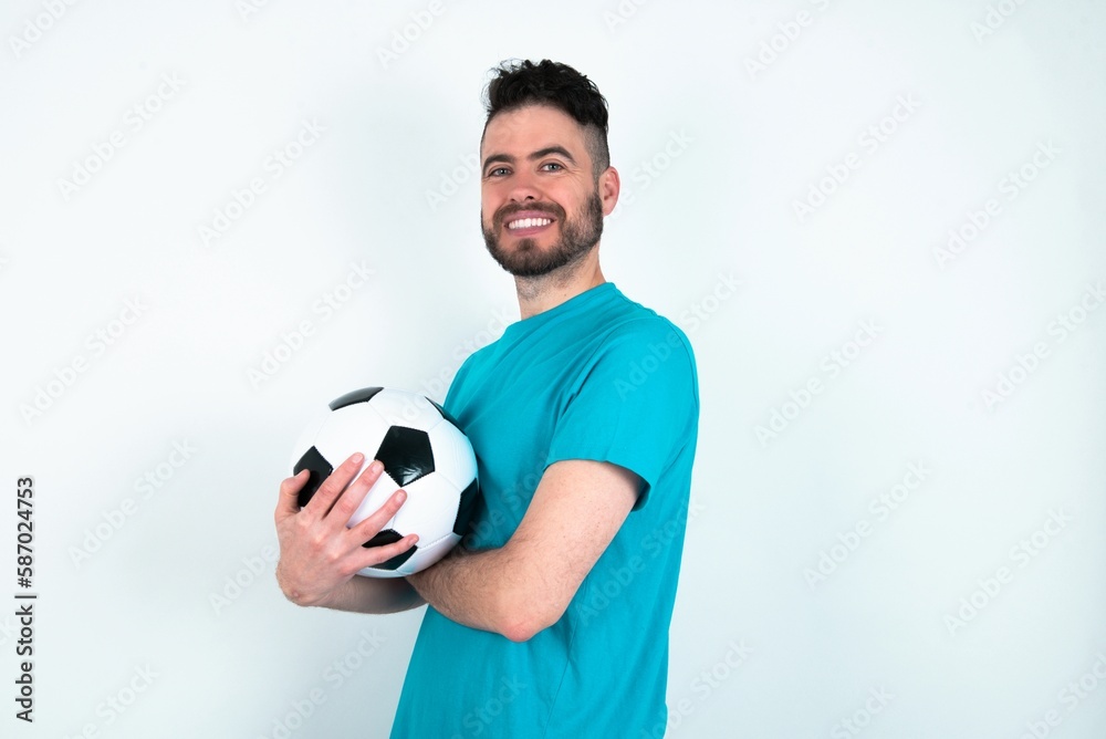 Young man holding a ball over white background happy face smiling with crossed arms looking at the camera. Positive person.