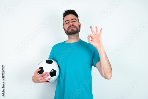 Young man holding a ball over white background relax and smiling with eyes closed doing meditation gesture with fingers. Yoga concept.