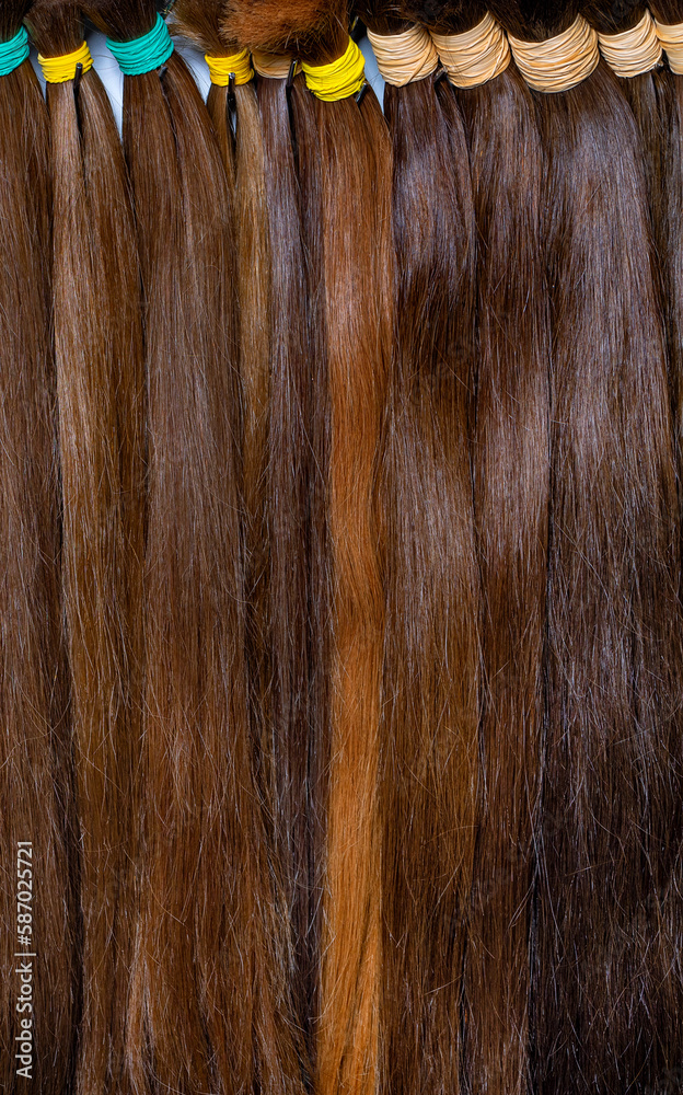 Buns of chocolate colored hair for extensions and hairstyles. Vertical image. Closeup.
