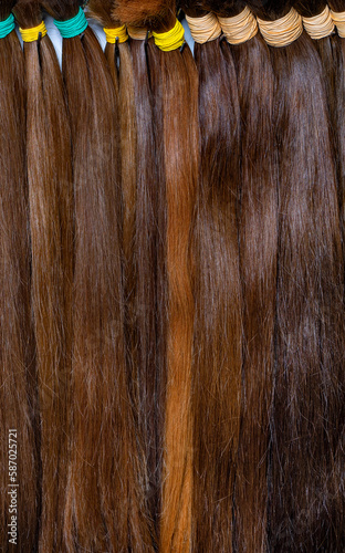 Obraz na płótnie Buns of chocolate colored hair for extensions and hairstyles. Vertical image. Closeup. w salonie