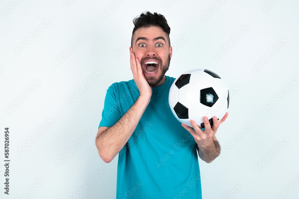 Young man holding a ball over white background Pleasant looking cheerful, Happy reaction Young man holding a ball over white background Pleasant looking cheerful, Happy reaction