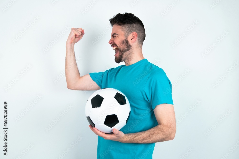 Profile photo of Young man holding a ball over white background supporting soccer team World Cup 2022 raise fist shouting