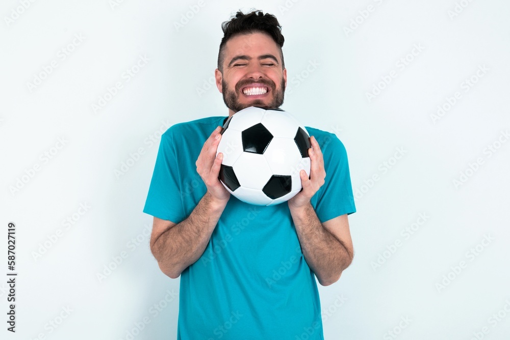 Young man holding a ball over white background grins joyfully, imagines something pleasant, copy space. Pleasant emotions concept. Young man holding a ball over white background grins joyfully, imagines something pleasant, copy space. Pleasant emotions concept.