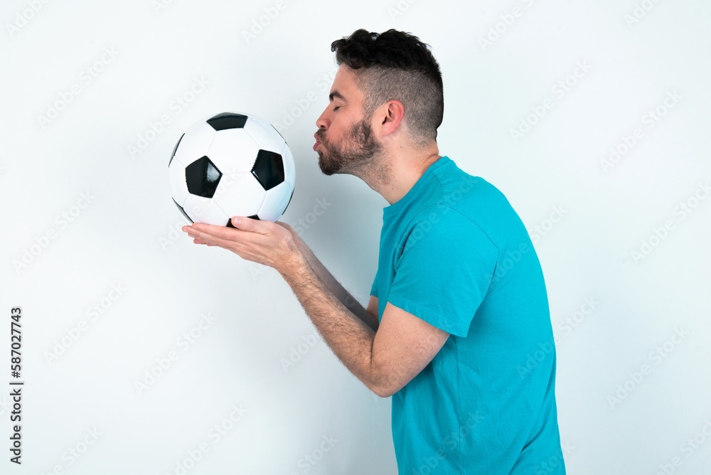 Profile side view, portrait of attractive Young man holding a ball over white background sending air kiss