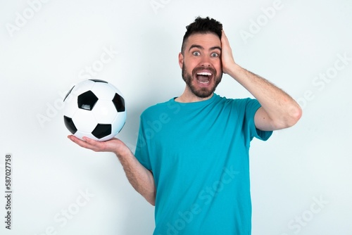 Shocked amazed surprised Young man holding a ball over white background hold hand offering proposition