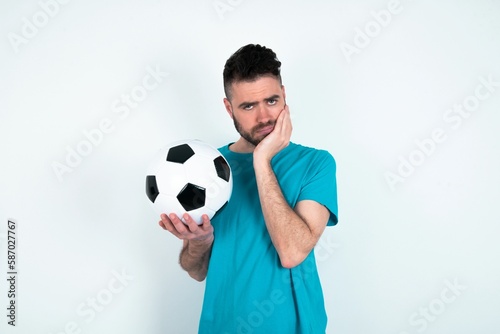 Portrait of sad Young man holding a ball over white background hands face