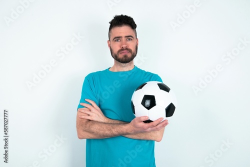 Confident Young man holding a ball over white background with arms crossed looking to the camera