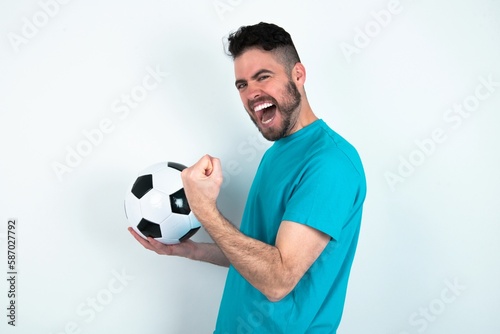 Profile side view portrait Young man holding a ball over white background celebrates victory