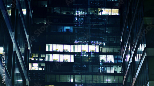 Pattern of office buildings windows illuminated at night. Glass architecture  corporate building at night - business concept. Blue graphic filter.