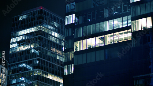 Pattern of office buildings windows illuminated at night. Glass architecture ,corporate building at night - business concept. Blue graphic filter.