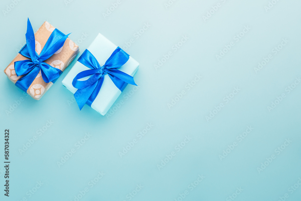 A pair of gift boxes with a blue ribbon on a blue background. A pair of gift boxes with a blue ribbon on a blue background.