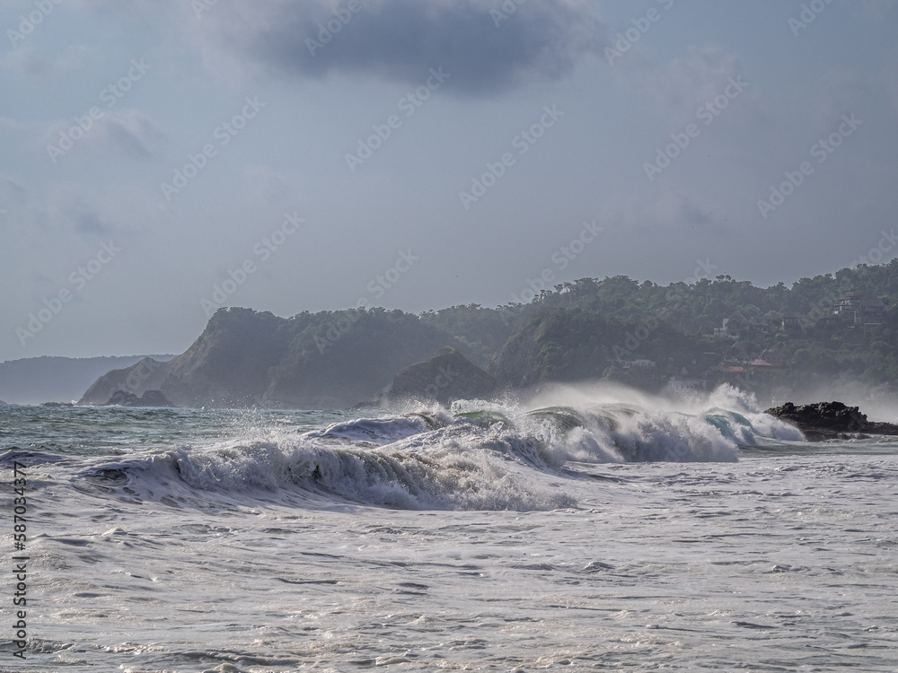 big waves against the background of forested hills