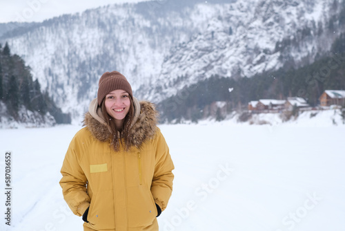 Beauty Girl smile in winter mountains Outdoor. Flying Snowflakes. Beauty young woman Having Fun in Winter Park. Good mood while spending time outdoors on snowy winter day in mountains
