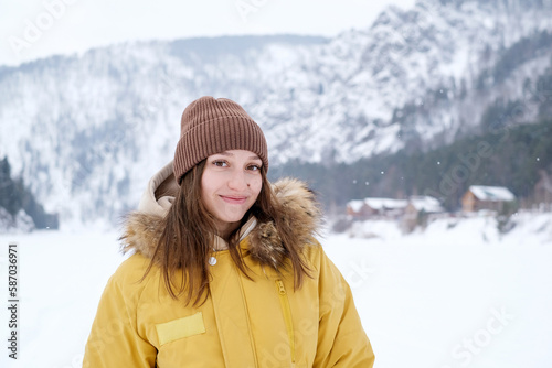 Beauty Girl smile in winter mountains Outdoor. Flying Snowflakes. Beauty young woman Having Fun in Winter Park. Good mood while spending time outdoors on snowy winter day in mountains