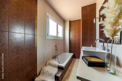 Modern bathroom design with white bathtub with steps, sink, mirror and decoartion. Browl and white tiled walls. photo