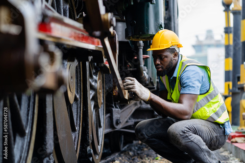 Photos American engineer male engineer inspects and inspects trains and inspects work in a railway station wearing a safety suit and helmet to work