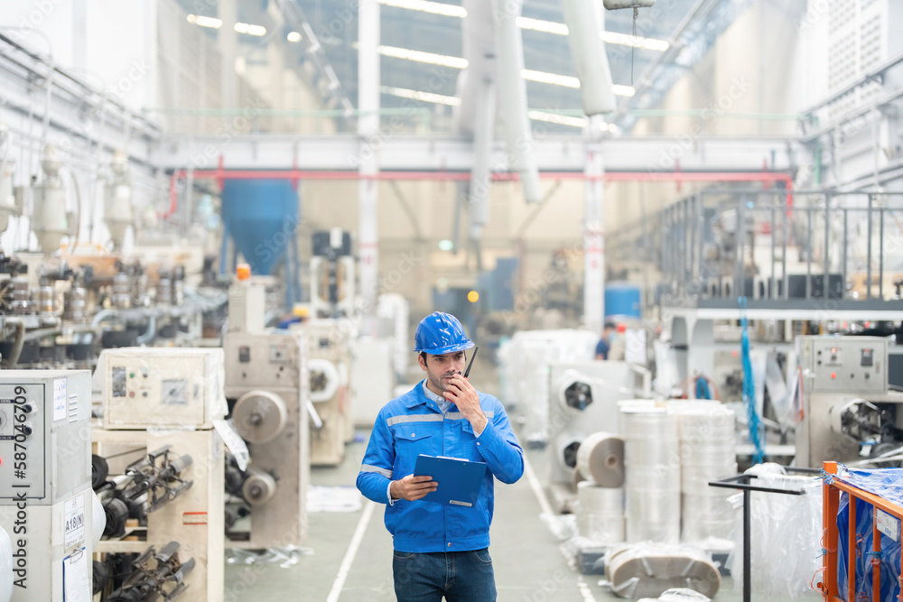 European white male engineer Powering the radio to do business and walking in the industrial factory Around there are machines working. He wore a uniform and helmet. European white male engineer Powering the radio to do business and walking in the industrial factory Around there are machines working. He wore a uniform and helmet.