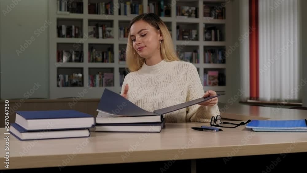 A young beautiful girl college student reads interesting literature in the campus library. A young beautiful girl college student reads interesting literature in the campus library.