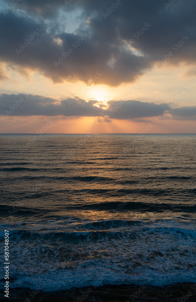 Seascape: sunset over water surface. Aerial view. Waves lapping on the shore