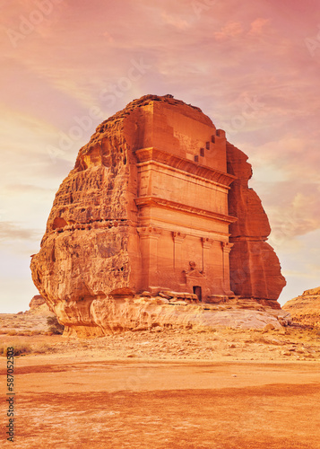 Tomb Lihyan Son of Kuza, Lonely Castle or Qasr al-Farid at Hegra, Saudia Arabia - most popular landmark in Mada'in Salih archaeological site, sandy desert landscape around - toned in orange pink color photo