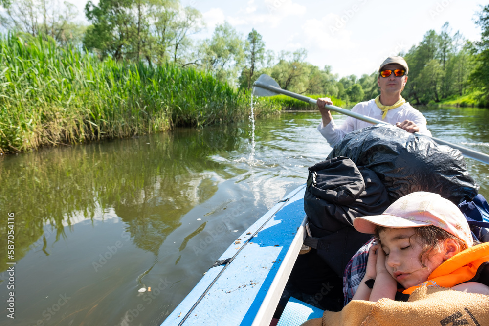 Family kayak trip. Father and daughter rowing boat on the river, a water hike, a summer adventure. Eco-friendly and extreme tourism, active and healthy lifestyle Family kayak trip. Father and daughter rowing boat on the river, a water hike, a summer adventure. Eco-friendly and extreme tourism, active and healthy lifestyle