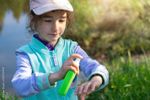 Girl uses a remedy for mosquitoes and biting insects in nature. Protection of the skin from tick bites, gadflies, blood-sucking pests, a means for children without allergens for outdoor camping