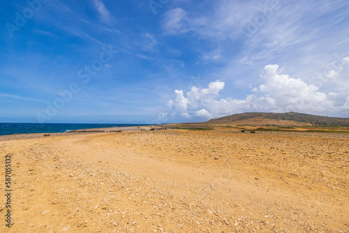 Beautiful nature landscape backgrounds. Sandy off-road merging with white clouds in blue sky. Aruba. 