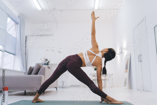 Slim anonymous woman doing yoga in living room