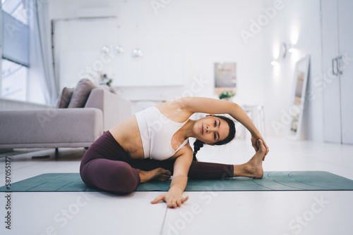 Slim woman doing revolved head to knee yoga in pose