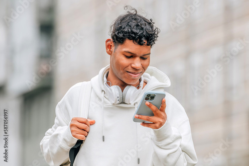 young latino man in the street looking at mobile phone or smartphone