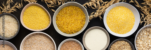 Various grain cereals in bowls banner, top view on a brown background with bowls of cereals and ears of oats