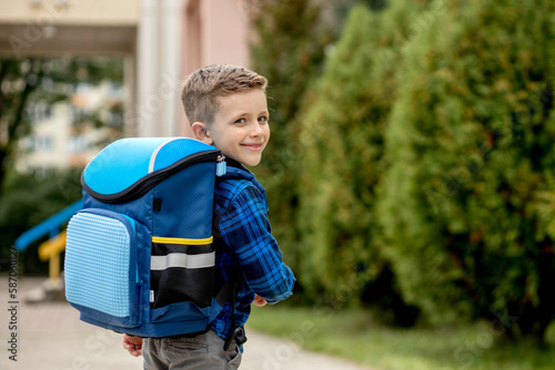 Little first grader with a blue backpack goes to school