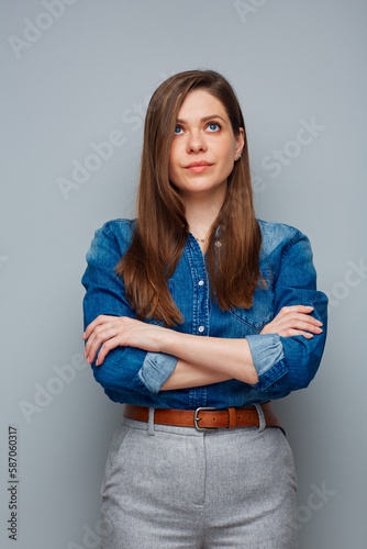 Serious woman in casual blue shirt looking up, isolated portrait.